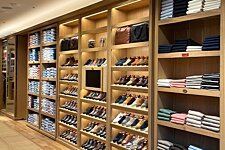 Interior de Bexley: estantería con zapatos de vestir, deportivas y camisas perfectamente dobladas.