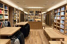 Vista central de la tienda Bexley en Marsella con mobiliario de madera, probadores y estantes organizados.