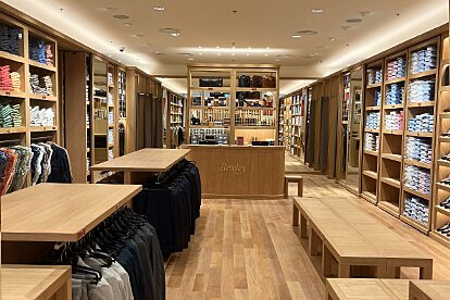 Vista central de la tienda Bexley en Marsella con mobiliario de madera, probadores y estantes organizados.