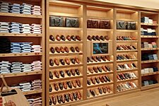 Inside Bexley store with leather shoes and folded shirts neatly displayed on wooden shelves.