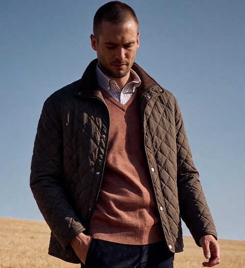 Man wearing a brown quilted jacket over a V-neck pullover