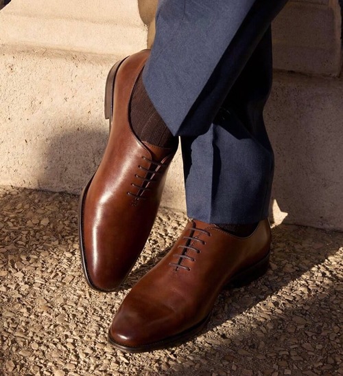Brown leather Oxford shoes worn with blue trousers