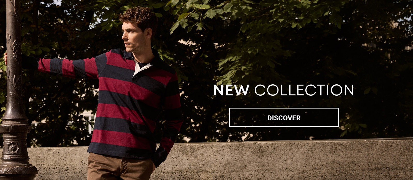 Man wearing a burgundy and navy striped rugby shirt with brown trousers