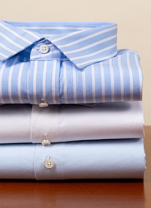 Folded men’s cotton shirts, striped and plain styles.