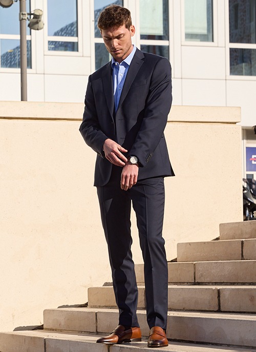 Man wearing a navy blue suit in an urban formal setting.