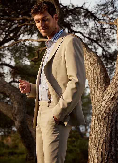 Man wearing a beige suit with a striped shirt, an elegant outfit for ceremonies
