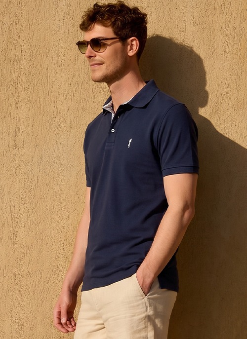Man wearing a navy short-sleeved polo shirt paired with light trousers for a smart-casual look