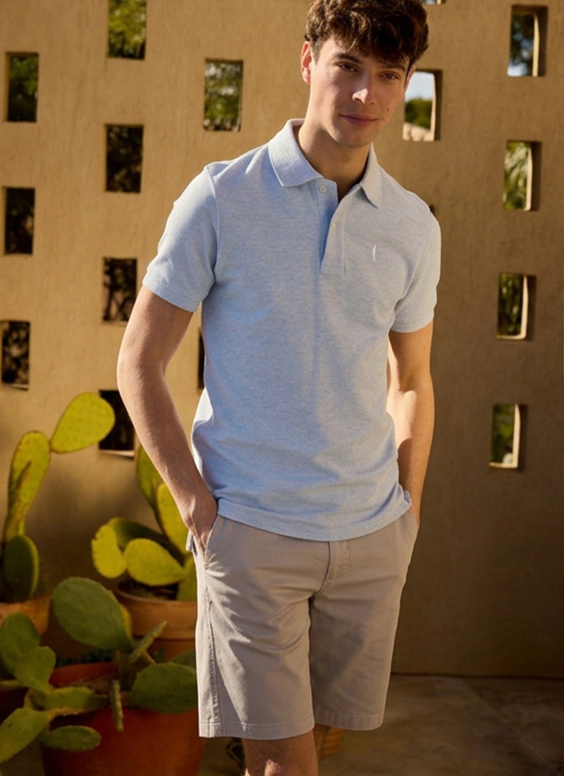 Man in a light blue polo shirt and beige shorts